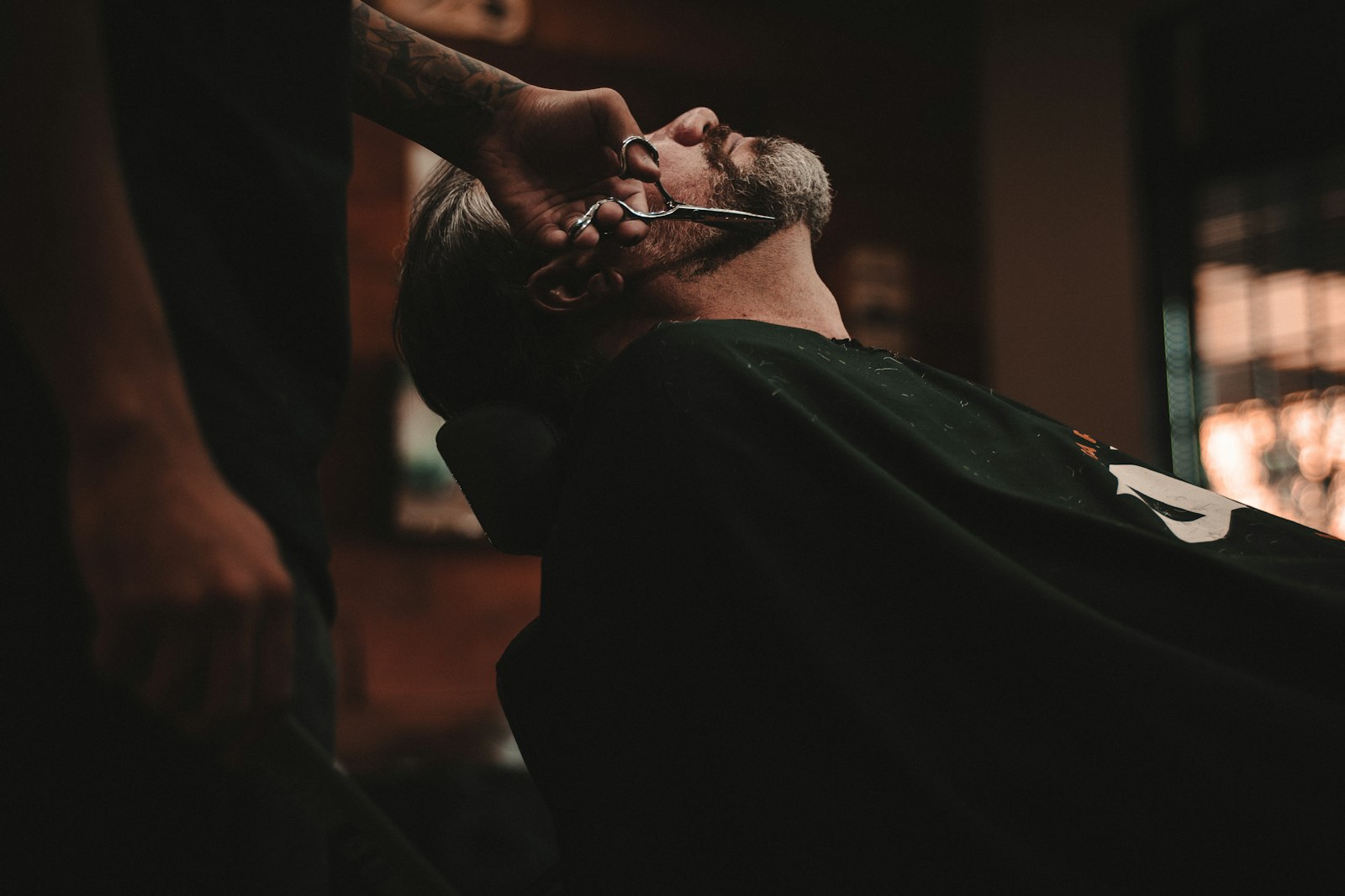 A barber finishing a beard line with scissors at The Cut Co on Karangahape Road