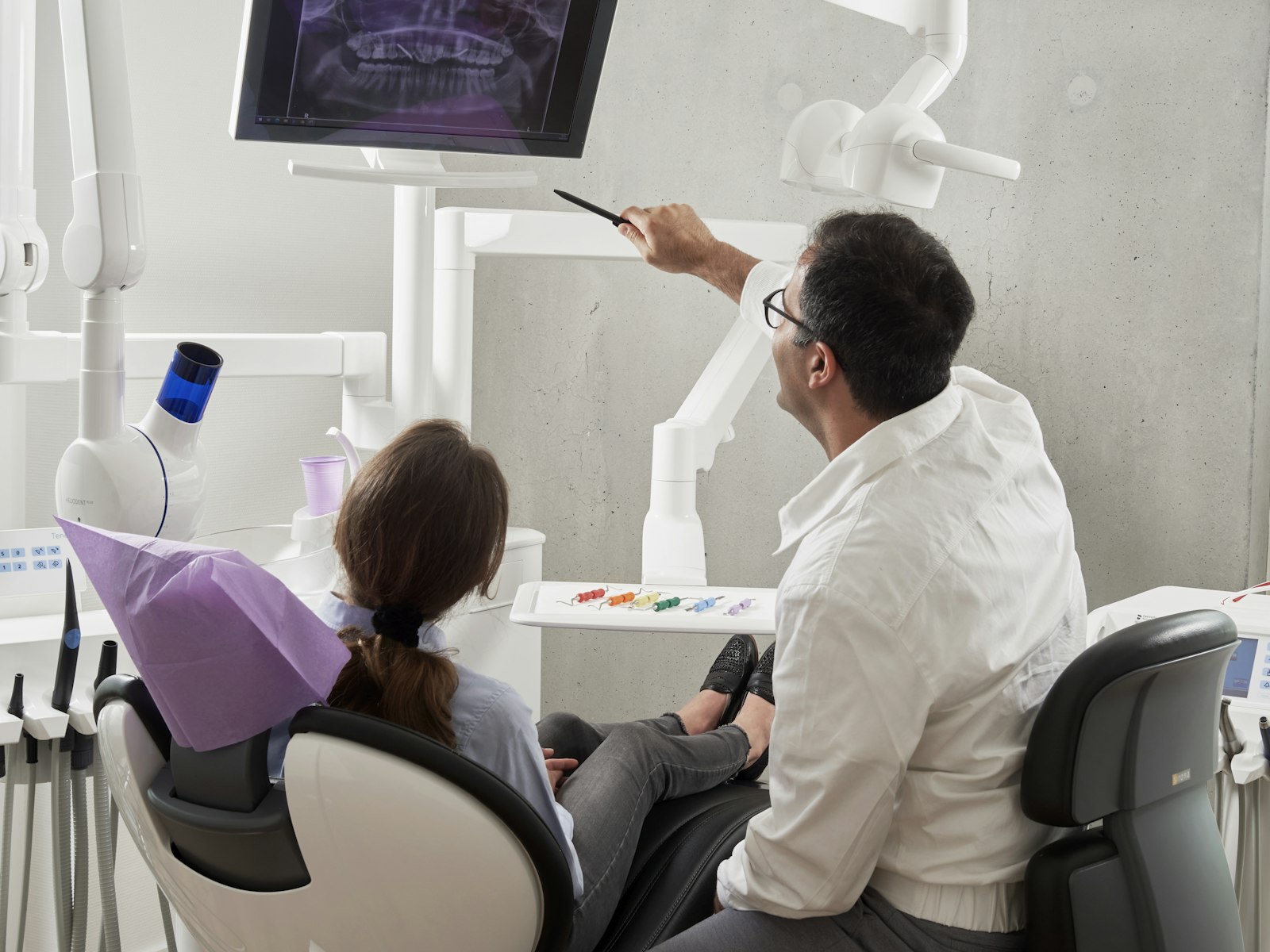A dentist gently talking a patient through their X-ray at the chair