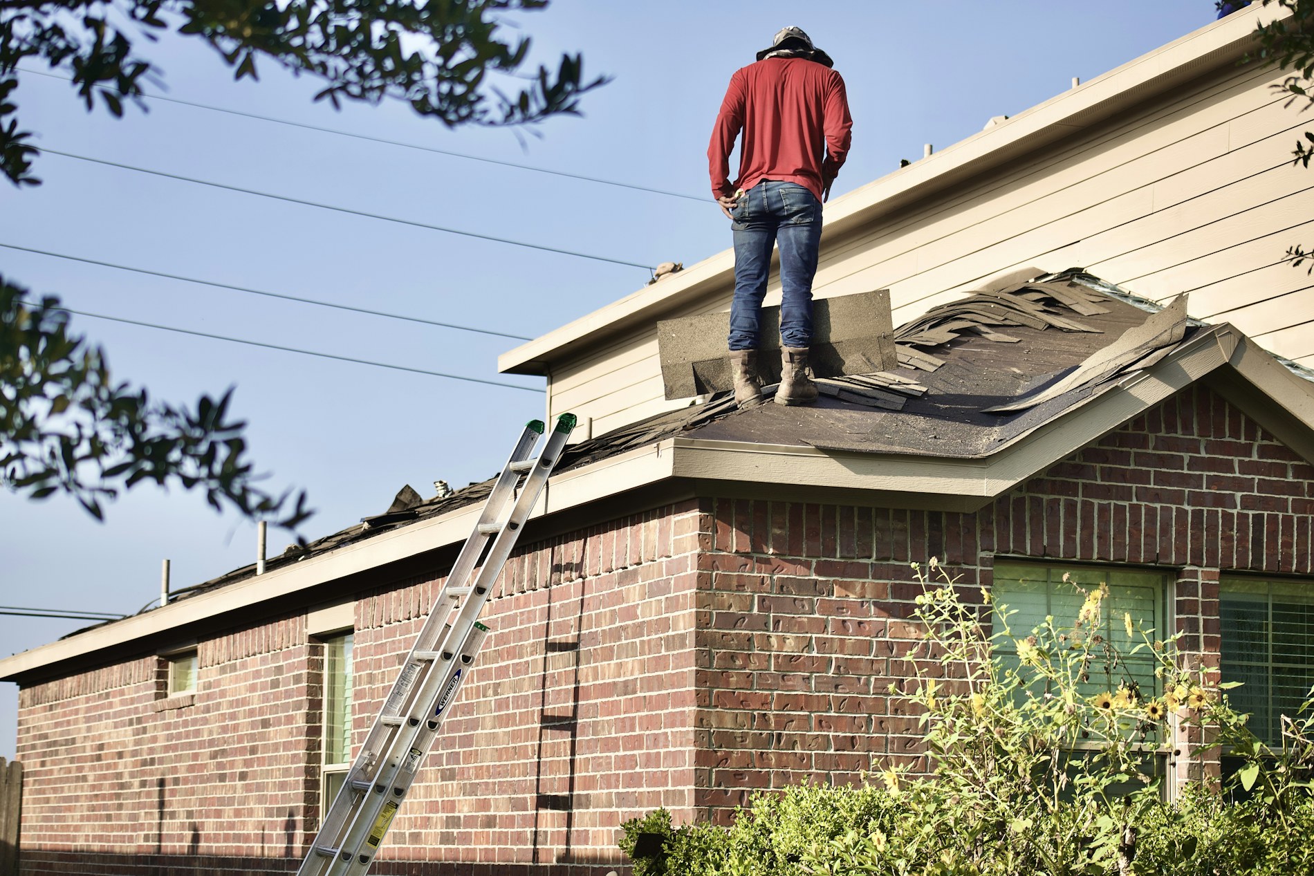Roofer working on a residential pitched roof, stripping and re-laying the surface