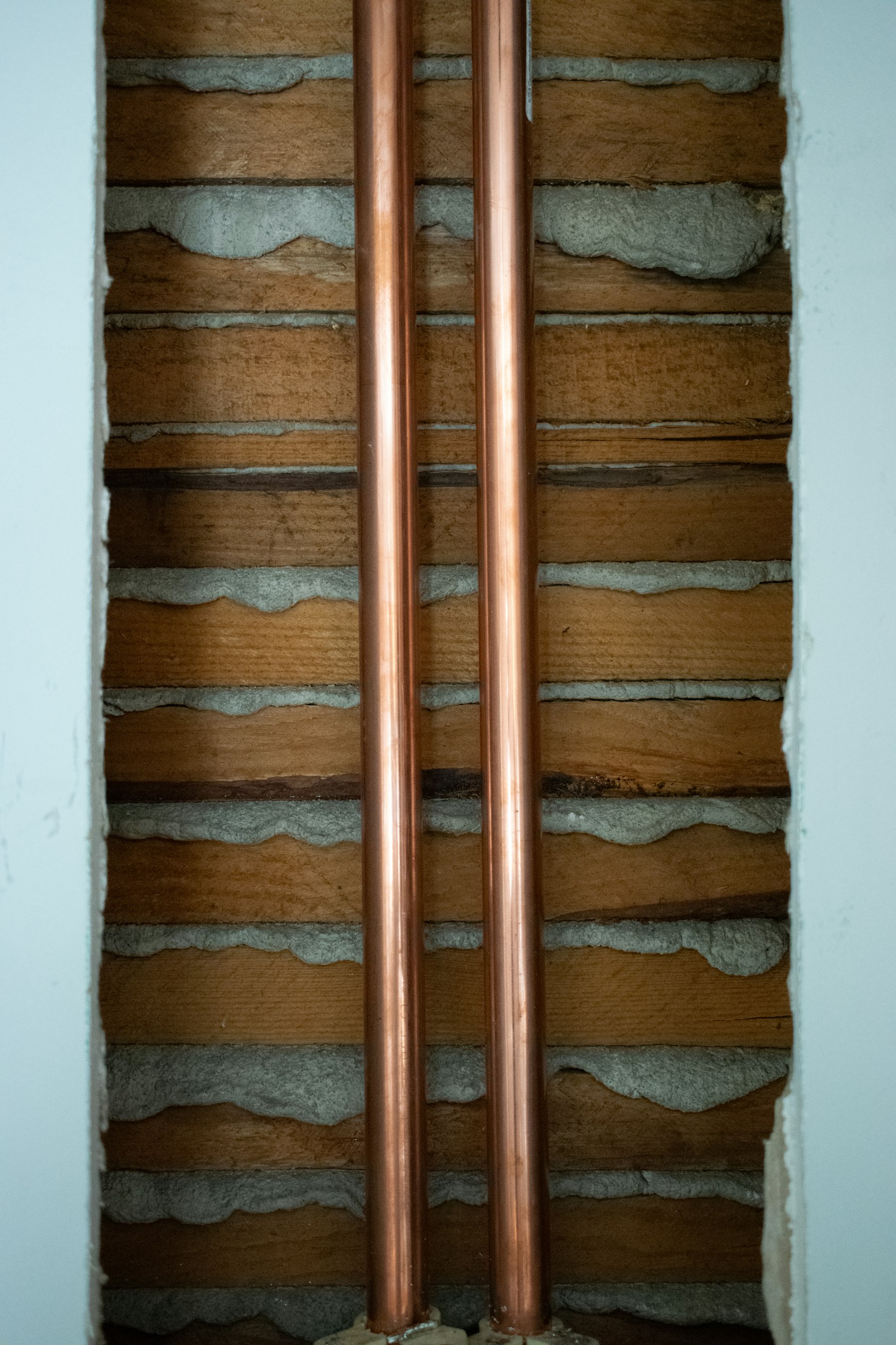 Two new copper pipes run side by side inside a Pakuranga wall cavity