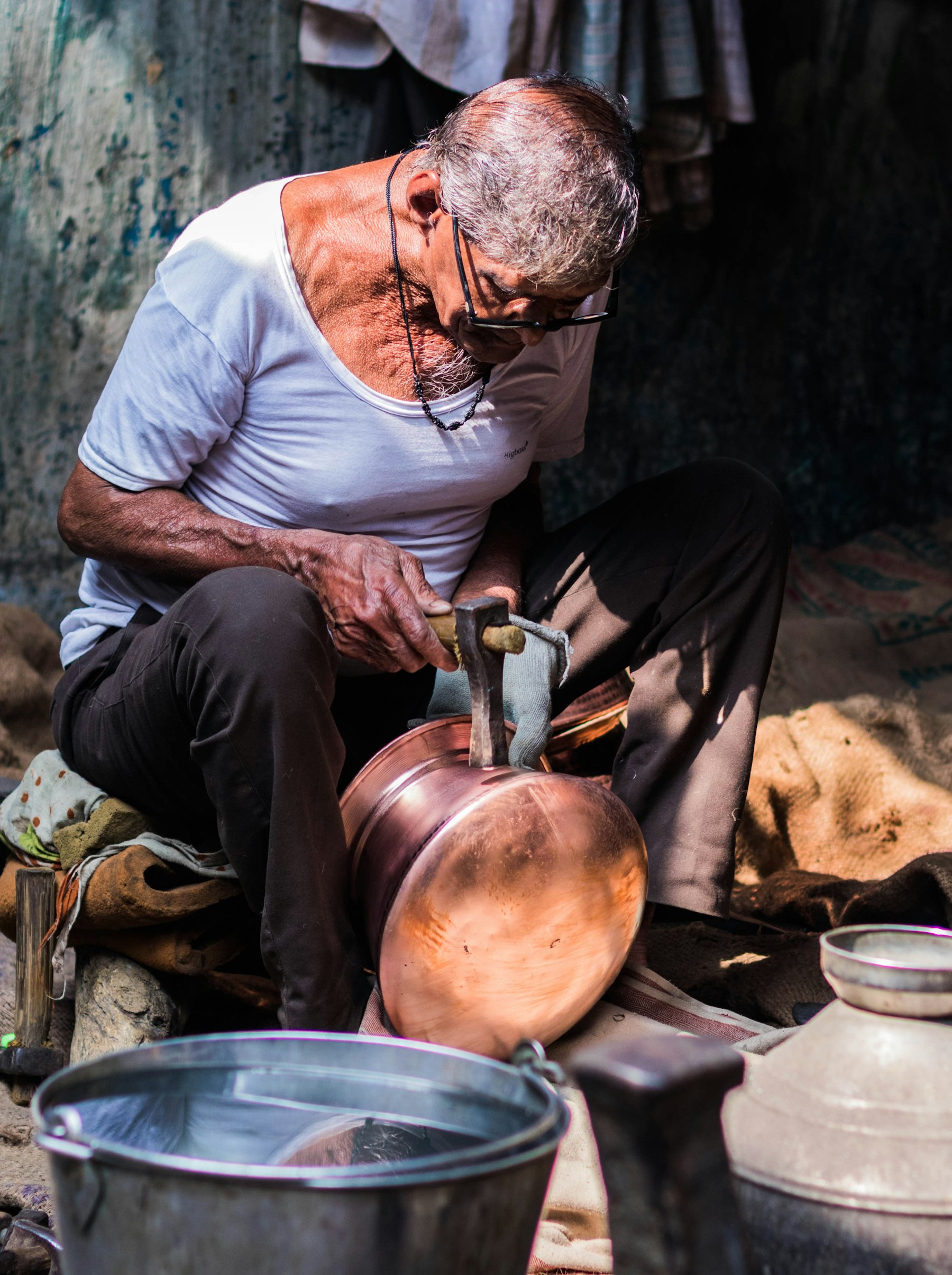 An older tradesman working copper by hand