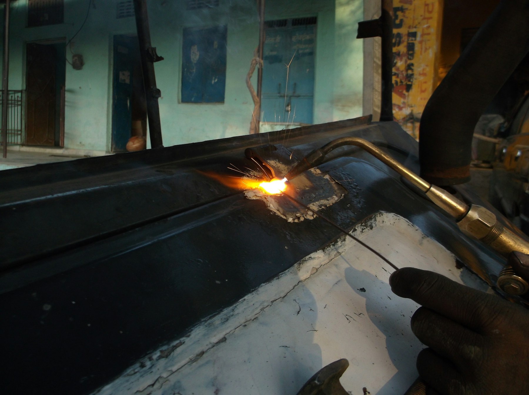 A brazing torch joining metal, a plumber's hand steadying the work