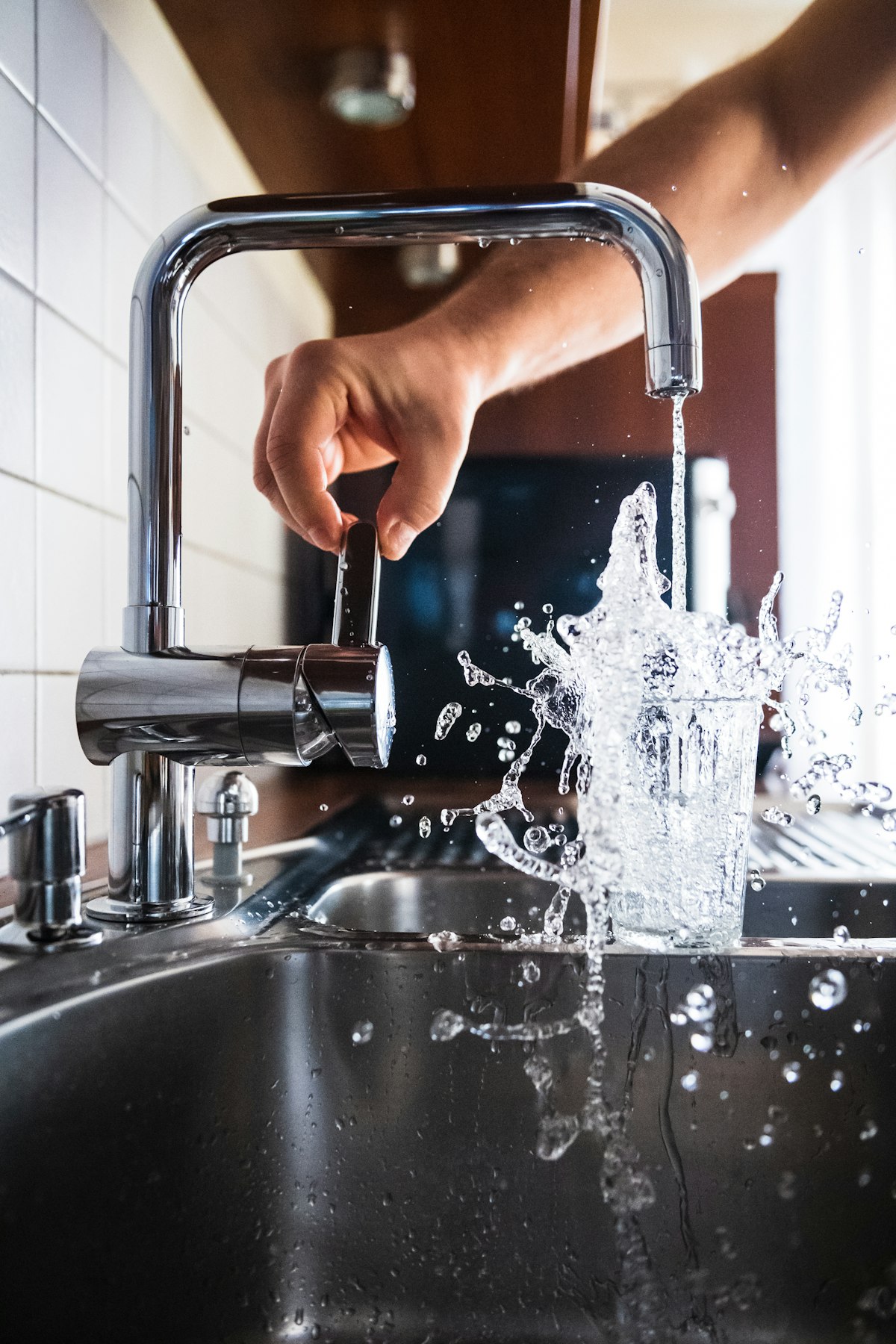 A hand carefully turning a kitchen tap as water runs